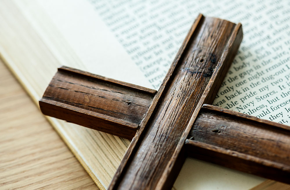 close up of wooden cross sitting on a bible.